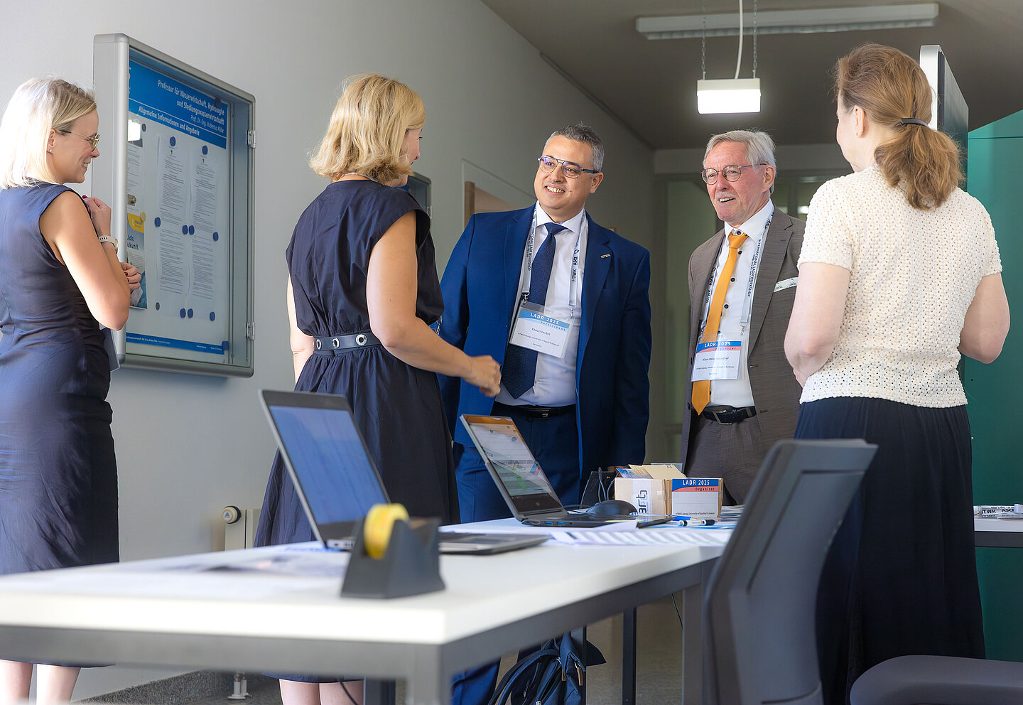 Männer und Frauen stehen um einen Tisch herum und unterhalten sich