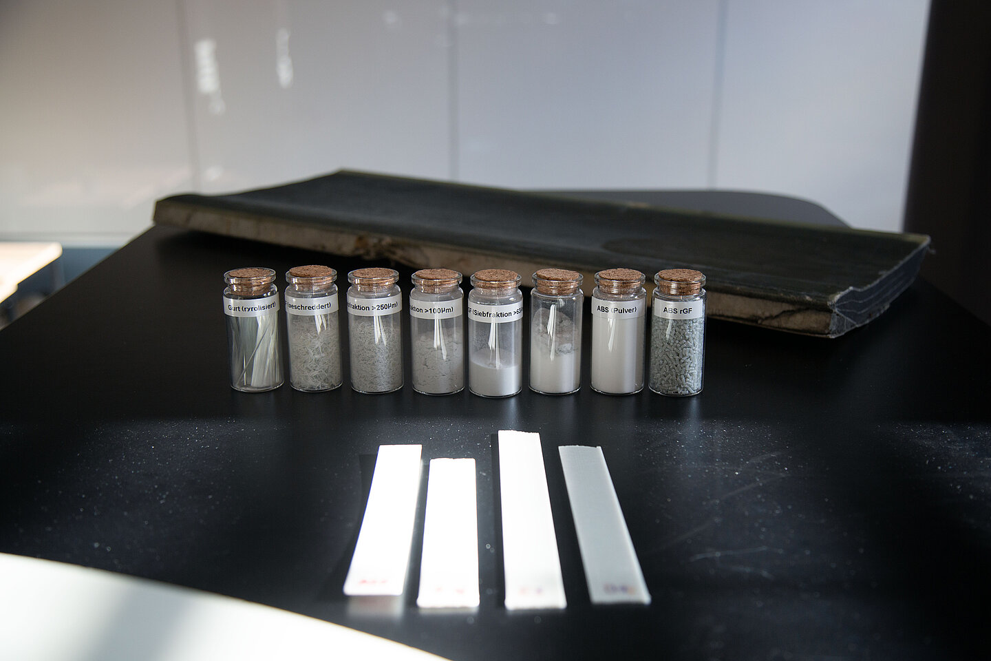 Fläschchen mit grauem Pulver stehen auf einem Tisch