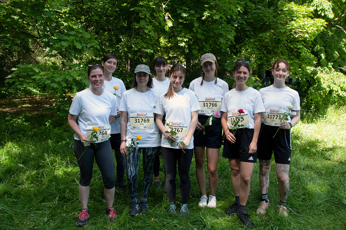 Frauenlauf 8 Frauen mit Startnummern und Sportsachen und Blumen