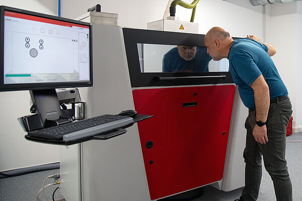 ein Mann schaut in einen Drucker rein