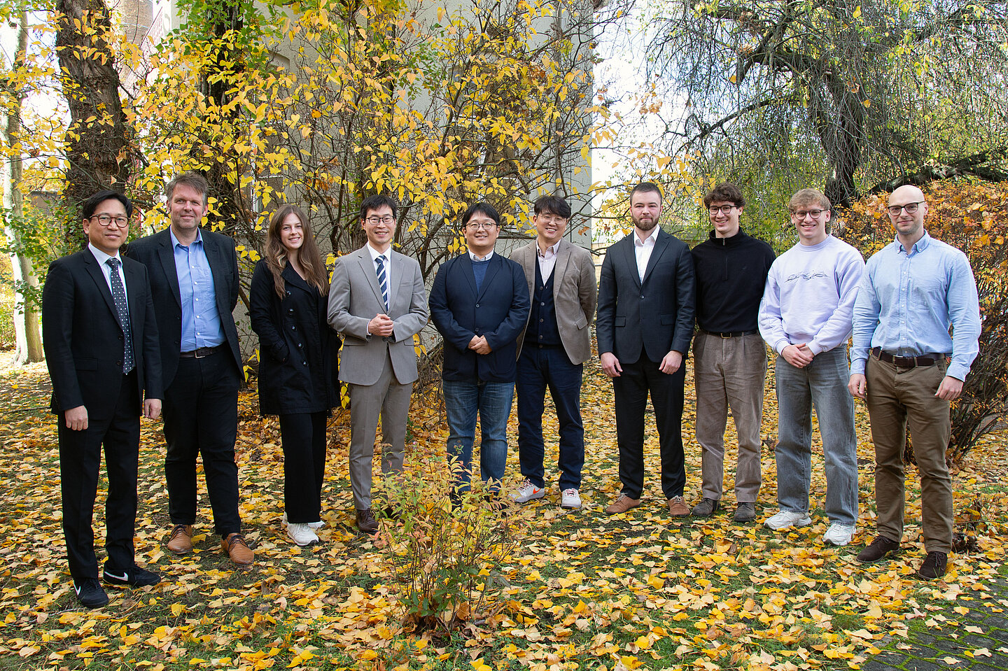 9 Männer und 1 Frau stehen für ein Gruppenbild nebeneinander