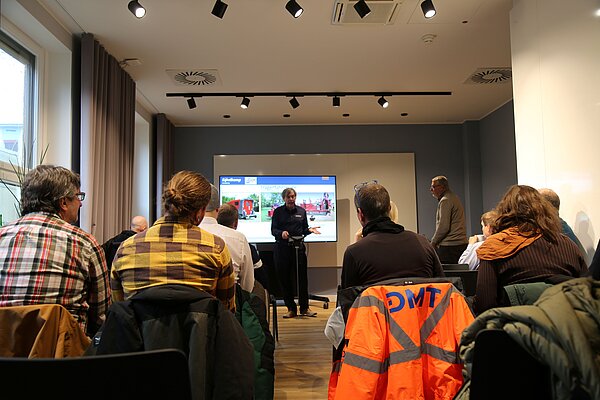 Mann steht vor sitzendem Publikum und hält Vortrag