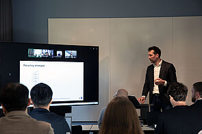 ein Mann hält einen Vortrag neben einem großen Bildschirm