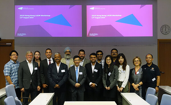 LADR-Workshop Hongkong Männer und Frauen stehen vor einer Wand für ein Gruppenbild