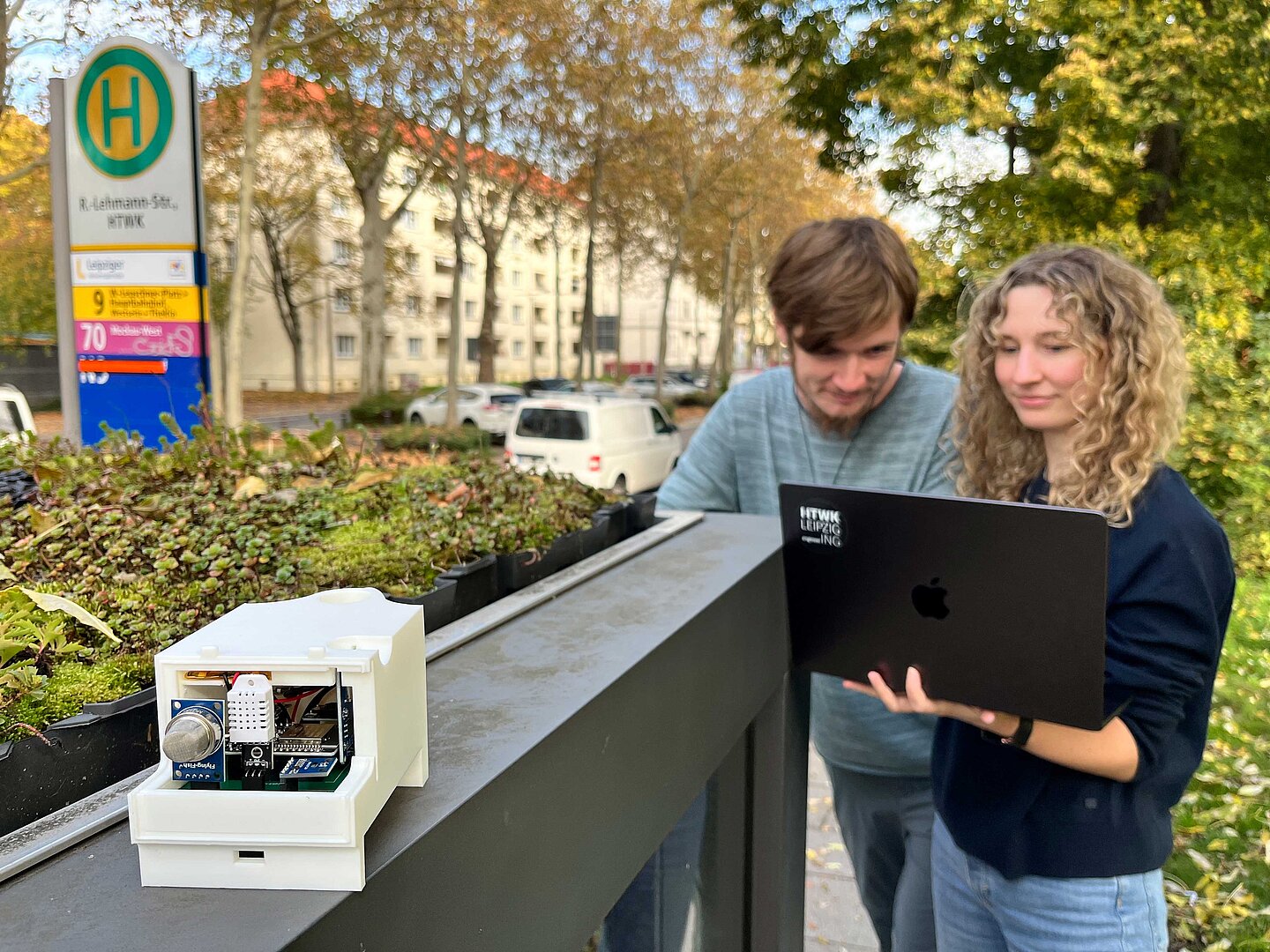 Zu sehen sind die wissenschaftliche Mitarbeiterin Stefanie Penzel und die studentische Hilfskraft Philipp Lorenz an der Haltestelle „HTWK Leipzig“