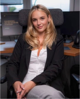 Interviewpartnerin Adelina Kuliqi sitzend in einem Büro, Blick zur Kamera